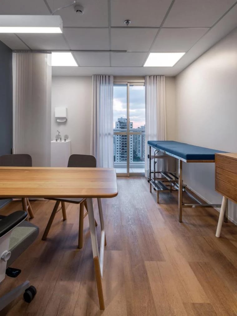 Sala de atendimento com mesa e maca de exame